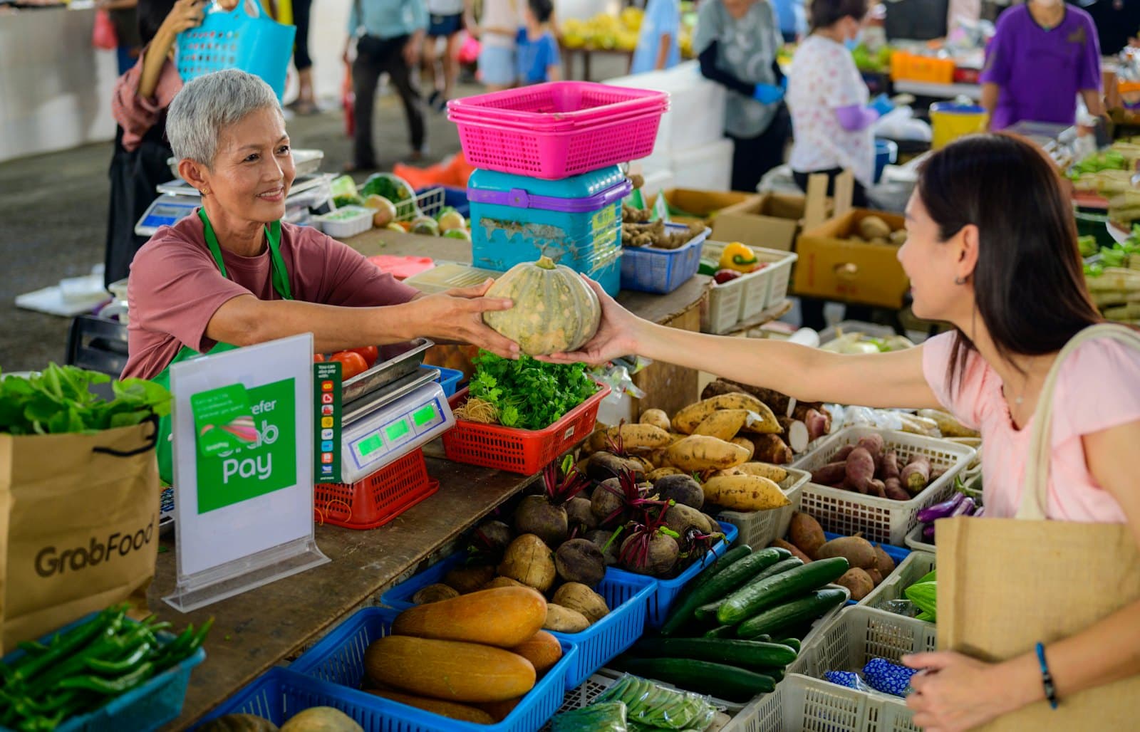 A market vendor handing fresh vegetables to a customer
